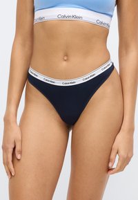 Σκούρο μπλε εσώρουχο σλιπ με μαλακή λευκή ελαστική μέση με μαύρη ένδειξη "Calvin Klein". Κατασκευασμένο από απαλό ύφασμα με ελάχιστη κάλυψη.