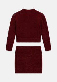 Ensemble en tricot bordeaux composé d'un pull et d'une jupe avec motif torsadé, poignets côtelés et large ceinture. Tissu texturé au look confortable.