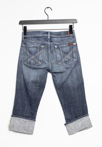 Jeans de denim en un lavado medio. Con puños enrollados, doble bolsillo trasero con patrones cosidos y una cintura con botón tradicional.