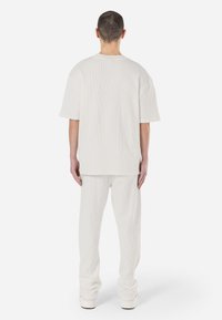 Lightweight, ribbed white oversized t-shirt paired with matching ribbed pants, featuring a relaxed fit and soft texture, viewed from the back.
