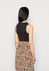 Top cropped preto emparelhado com uma saia floral multicolorida. O tecido é suave, com um formato ajustado, apresentando um decote redondo e design sem mangas.