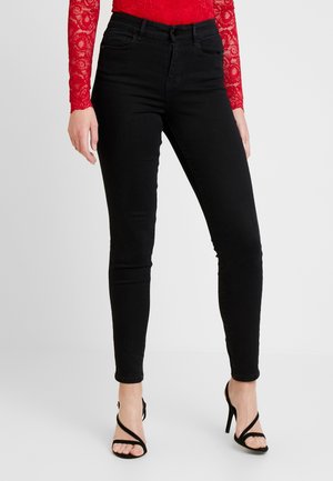 Jeans skinny negros de denim, con cintura de altura media, diseño de cinco bolsillos y corte slim hasta el tobillo.