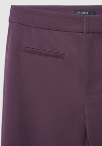 Pantaloni intrecciati viola con vita piatta, tasche laterali e texture liscia. Etichetta con la scritta "CALLIOPE," taglia S.