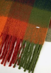 Wełniany szalik z wzorem w kratę w kolorach pomarańczowym, zielonym i szarym, z frędzlami na końcach oraz małą tkana metką z nazwą marki.