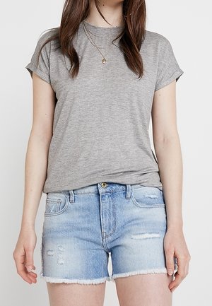 T-shirt gris à manches courtes associé à un short en denim bleu délavé avec ourlet effiloché et détails usés.