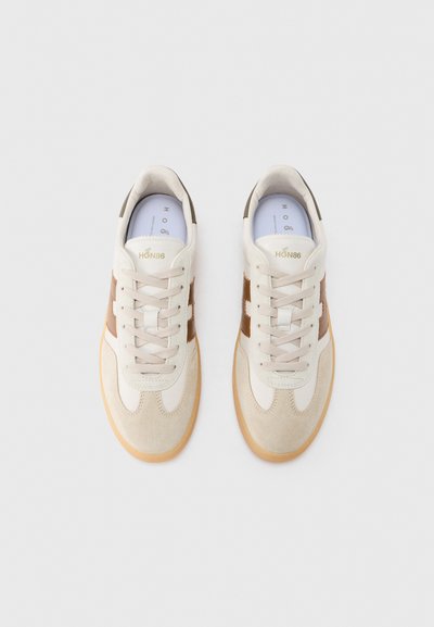 Αθλητικά παπούτσια με μπεζ επάνω μέρος από σουέτ και δέρμα, καφέ πλαϊνές λεπτομέρειες, ανοιχτό γκρι κορδόνια και σόλα από καουτσούκ σε χρώμα τσίχλας. Διαθέτουν επενδεδυμένο γιακά.