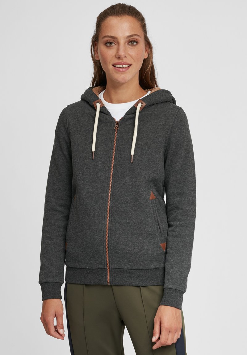 Haut à capuche gris foncé avec fermeture éclair, cordons crème et accents en cuir marron. Texture douce et poches latérales. Design décontracté.