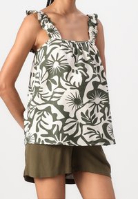 Top senza maniche con motivo floreale verde e bianco, caratterizzato da spalline arricciate e vestibilità ampia. Realizzato in tessuto leggero.