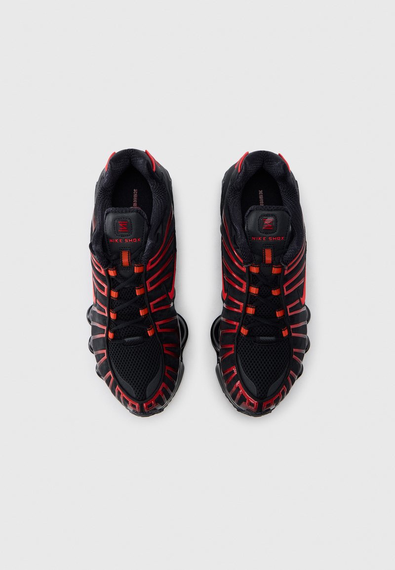 Black and red athletic shoes featuring a mesh upper, prominent lacing system, cushioned sole, and distinctive Nike Shox heel design.