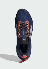 Mekonnavy juoksukengät hengittävällä verkkopinnalla, oransseilla yksityiskohdilla, heijastavilla raidoilla ja kuvioidulla pohjalla, varustettuna solmittavilla nauhoilla.