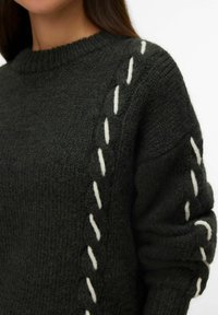 Maglione lavorato a maglia grigio scuro con una finitura testurizzata, caratterizzato da cuciture decorative bianche lungo le maniche e un classico scollo rotondo.
