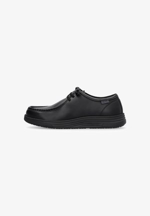 Chaussure décontractée en cuir noir à lacets avec semelle rembourrée et étiquette de marque sur le côté, présentée en profil latéral sur un fond blanc.