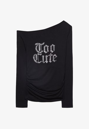 Sort langærmet skjorte med off-shoulder design. Har rynket side detalje og sølv rhinestone bogstaver der staver "Too Cute." Blød tekstur.