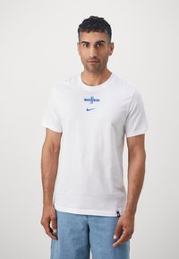 Weißes Baumwoll-T-Shirt mit kurzen Ärmeln, das ein blaues bedrucktes Logo und Akzente auf der Brust zeigt. Lässige Passform mit Rundhalsausschnitt.
