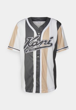 Chemise à manches courtes à boutons avec des rayures verticales noires, beiges et blanches, avec le texte "Kani est. 1989" sur la poitrine.