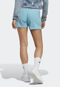 Light blue cotton shorts with a relaxed fit, paired with white athletic socks and sneakers, and a distressed denim jacket.