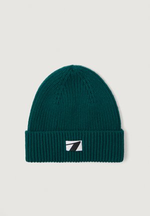 Gorro de malha teal com uma aba dobrada em canelado, com um rótulo branco e um gráfico preto na frente. Textura suave, design clássico.