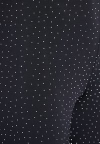 Juodos legginsai su tekstūruotu raštu, sudarytu iš mažų baltų taškelių visame audinyje. Medžiaga atrodo elastinga ir lygi.