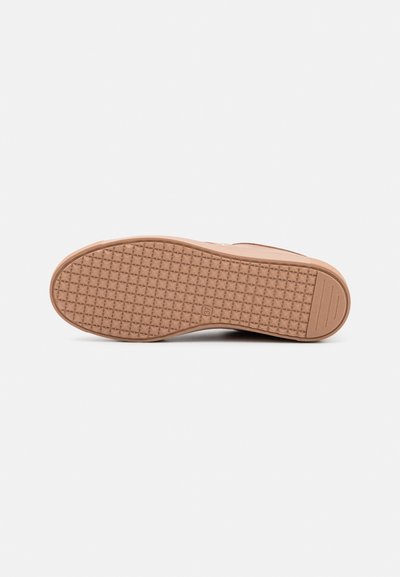 Suela de zapato de goma de color marrón claro con un patrón de agarre texturizado, forma redondeada y detalle del logo en el costado. Bordes suaves, construcción plana y acentos mínimos.