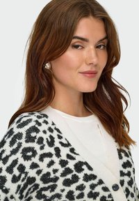 Leopardmönstrad kavaj i vitt och svart, med v-ringning, knappar och mjuk textur. Bärs över en enkel vit topp.