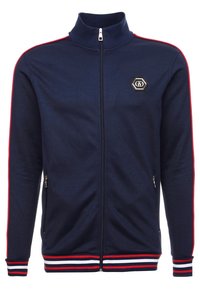 Chaqueta navy con cremallera y cuello alto, detalles en franja roja en las mangas, puños y dobladillo acanalados, bolsillos laterales y parche de logo hexagonal.