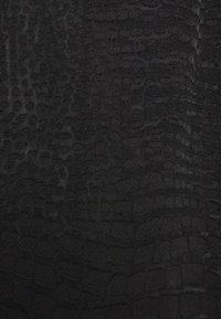 Tessuto nero testurizzato con un motivo coccodrillo, caratterizzato da diverse forme e dimensioni delle squame, creando un effetto tridimensionale.