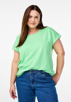 T-shirt verde chiaro a maniche corte con scollatura rotonda e maniche arrotolate, abbinato a jeans blu. Tessuto liscio, vestibilità casual.
