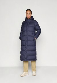 Tumši zils pūkains mētelis ar kapuci, ar garu, polsterētu dizainu, priekšā ar rāvējslēdzēju un divām sānu kabatām. Gluds, ūdens izturīgs materiāls.