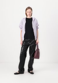 Lavendel capuchonjack, zwarte shirt, glanzende zwarte leren lookbroek en een bordeauxrode handtas. Zwarte flats maken de outfit compleet.