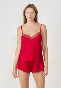 Ensemble de pyjama en satin rouge comprenant un débardeur avec une bordure en dentelle le long de l'encolure et un short assorti, tous deux dans une finition lisse et brillante.