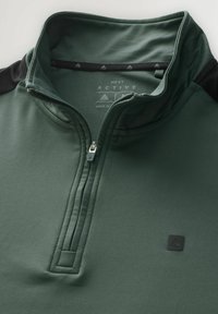 Un pulóver de media cremallera en verde oscuro, hecho de material suave. Presenta detalles en negro en los hombros, un pequeño logo y un cuello con cremallera. Textura lisa.