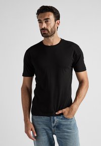 T-shirt noir à manches courtes en tissu doux avec un col rond classique, associé à un jean en denim bleu clair. Design simple et moderne.