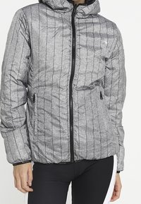 Grå puffjacka med vertikala svarta ränder, dragkedjestängning och huva. Har två sidofickor och en strukturerad yta.