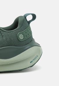 Nike React tenisice sa zelenim tekstilnim gornjim dijelom, gumeni potplat sa teksturiranim gripom i podstavljeni stražnji dio za potporu.