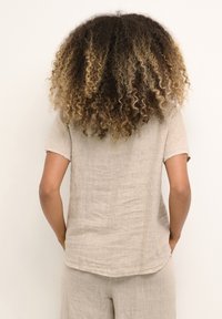 Chemise en lin beige clair à manches courtes, coupe décontractée, ourlet arrondi et détails subtils de texture, vue de dos.