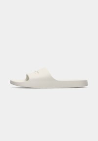 Hvit åpne tå sandaler med glatt matt overflate, buet design og subtil logo detalj på den øvre reimen. Minimalistisk estetikk.