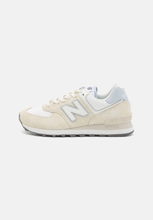 Beige und hellblaue Wildledersneaker mit weißen Akzenten und grauer Gummisohle. Verfügt über Schnürsenkel, einen gepolsterten Schaft und ein seitliches Logodesign.