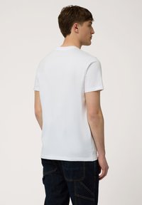 Witte katoenen T-shirt met een ronde hals, korte mouwen en een relaxte fit. De achterkant laat een gladde textuur en een eenvoudig ontwerp zien.