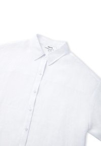 Camicia bianca di lino con colletto classico, bottoni davanti e maniche corte. Tessuto testurizzato con una finitura liscia e dettagli di design minimi.