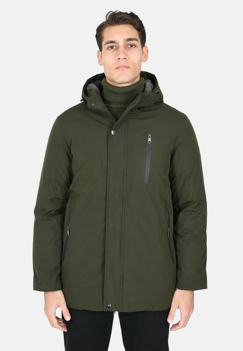 Parka verde oliva con cappuccio, tasca sul petto con zip, tasche laterali e una finitura testurizzata, indossata sopra un dolcevita scuro.