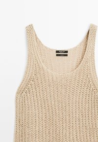 Top in lino beige senza maniche con un design a maglia morbida, scollatura ampia. L'etichetta all'interno indica che è realizzato al 100% in lino.