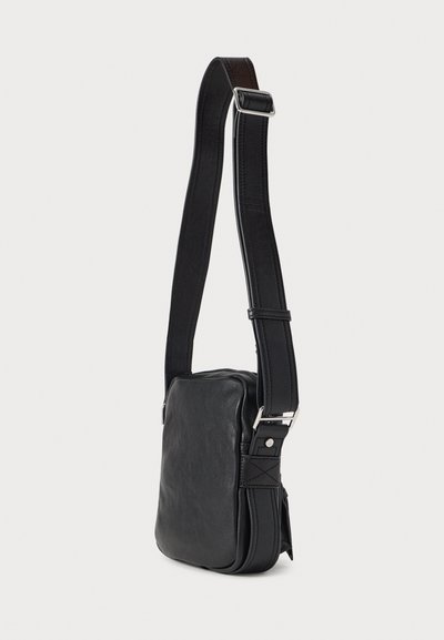 Černá kožená kabelka přes rameno s obdélníkovým tvarem, nastavitelným popruhem, stříbrným kováním a hladkou texturou. Má boční kapsu jako detail.