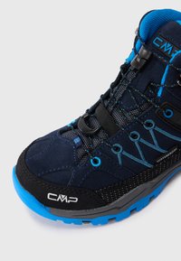 Tmavě modrá voděodolná turistická bota s modrými akcenty, černou podrážkou a logem CMP na špičce a jazyku, zkosená doprava na bílém pozadí.