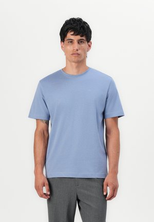 Light blue cotton t-shirt with a round neckline, short sleeves, and a subtle logo on the chest. Paired with gray pants.