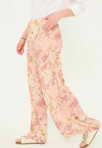 Floral wide-leg pants in pink and cream with green accents, made from lightweight fabric, featuring an elastic waistband and side pockets.