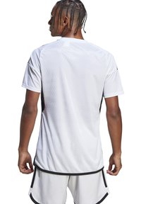 Weißes Sporttrikot mit strukturiertem Muster, kurzen Ärmeln und schwarzen Akzenten. Entworfen für Komfort und Leistung im Sport.