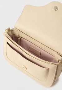 Μπεζ δερμάτινη τσάντα με υφή, χρυσά μεταλλικά στοιχεία και εσωτερική τσέπη με φερμουάρ, με απαλό ροζ φόδρα και μαγνητικό κλείσιμο.