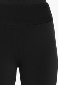 Svarta leggings med en bred, sömlös midjeband. Slät yta och figurnära design, med en hög midja utan synliga sömmar.