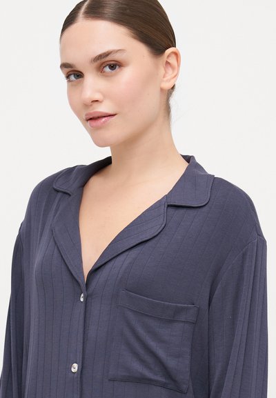 Navy blue, ribbed pajama top with a collar, button-down front, and chest pocket. Soft fabric with a relaxed fit.