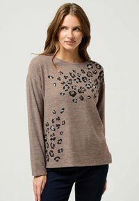 Brązowy sweter z długim rękawem z nadrukiem w lamparcie w czerni i szarości. Materiał wydaje się miękki, ma luźny krój i okrągły dekolt.